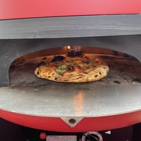 Fresh pizza cooking in wood-fired oven